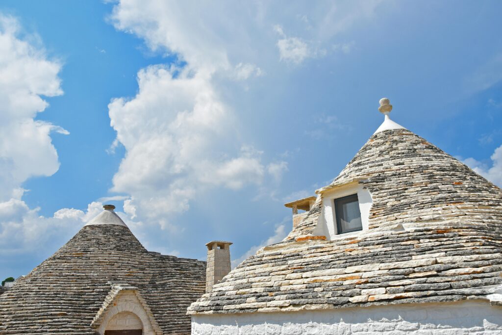 Traditional trulli houses in Puglia with unique conical roofs under a vibrant blue sky.
