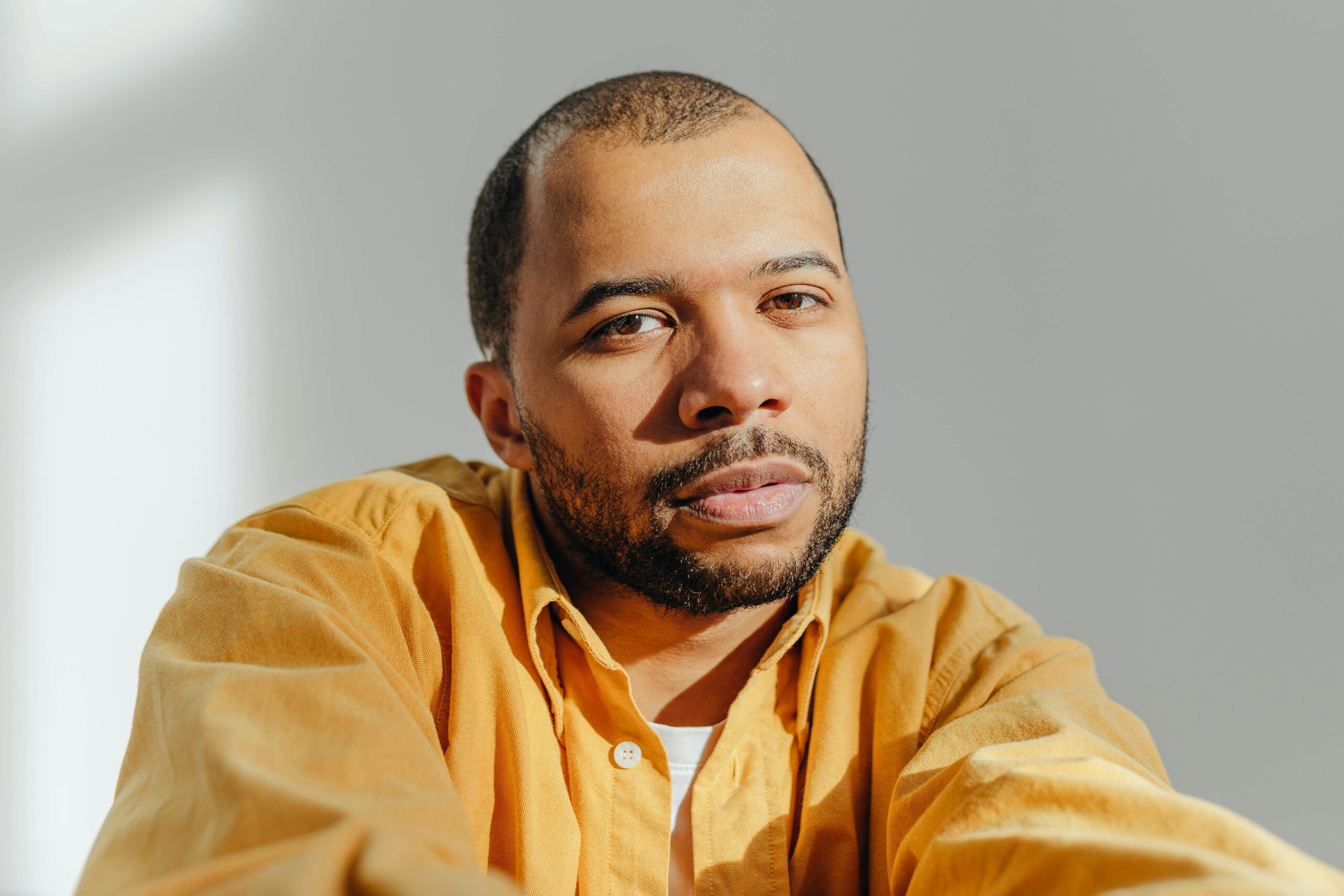 Portrait of a confident man in a studio with bright lighting and a neutral background.