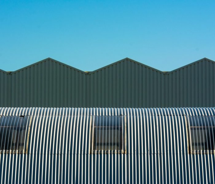 Industrial warehouse with corrugated and cylindrical roof design showcasing geometric structure.