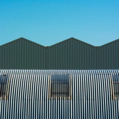 Industrial warehouse with corrugated and cylindrical roof design showcasing geometric structure.