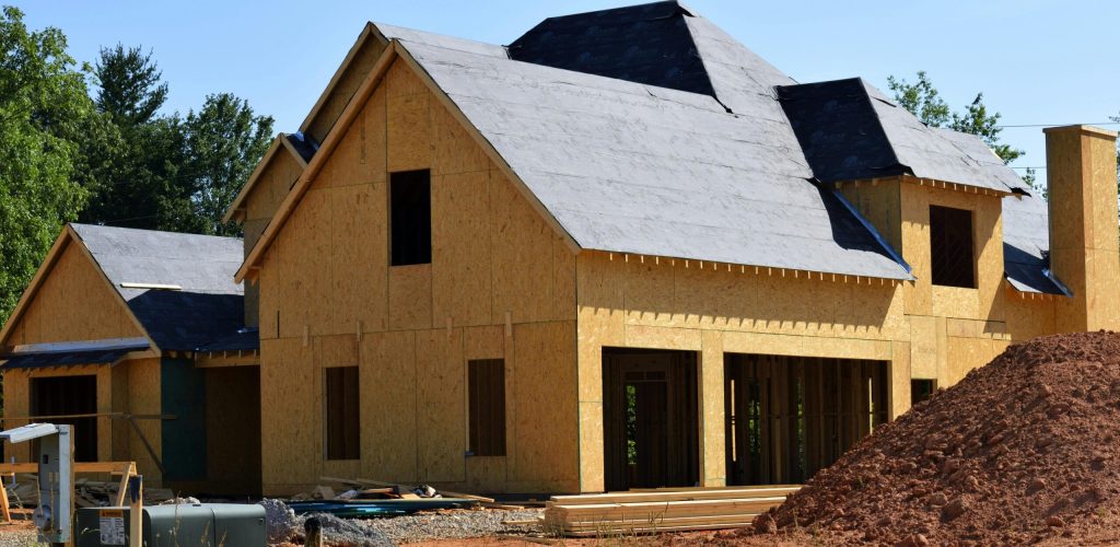 A partially built wooden house under construction, showcasing its progress and design in daylight.