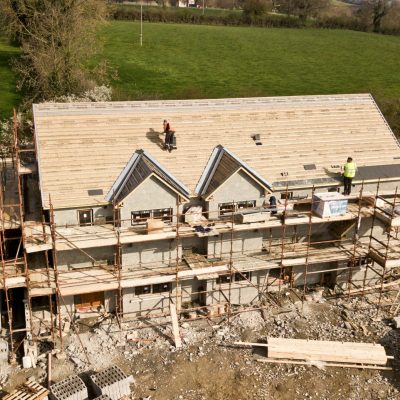 Aerial shot of a house under construction in Clonmel, Ireland. Workers on the roof.