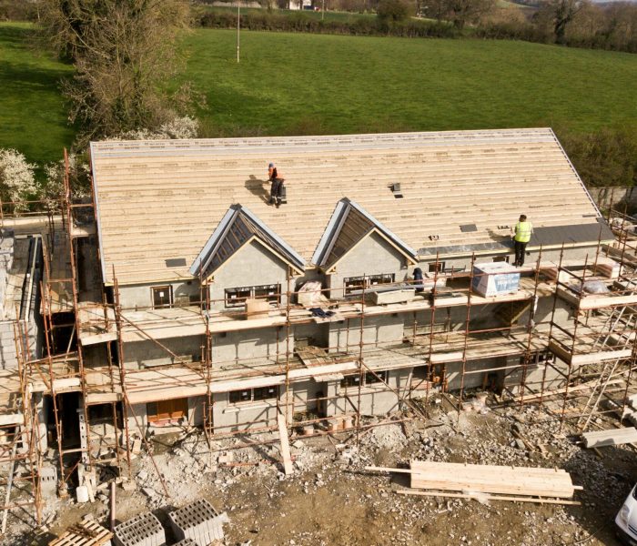 Aerial shot of a house under construction in Clonmel, Ireland. Workers on the roof.