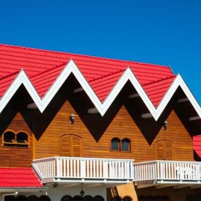 Charming home with red tile roof and wooden facade against clear sky.