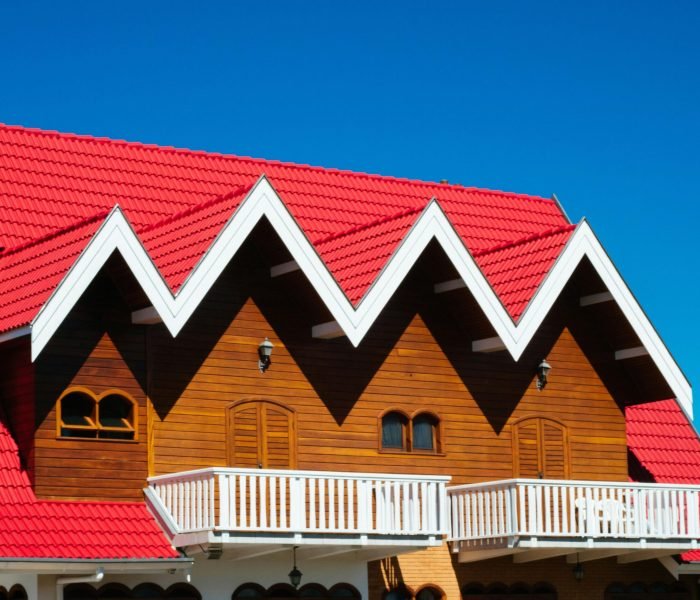 Charming home with red tile roof and wooden facade against clear sky.