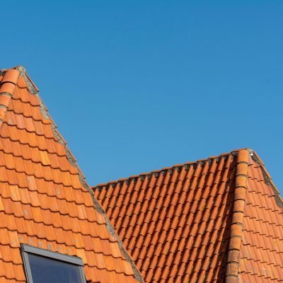 Close-up of red tiled roofs under a clear blue sky, showcasing architectural design.
