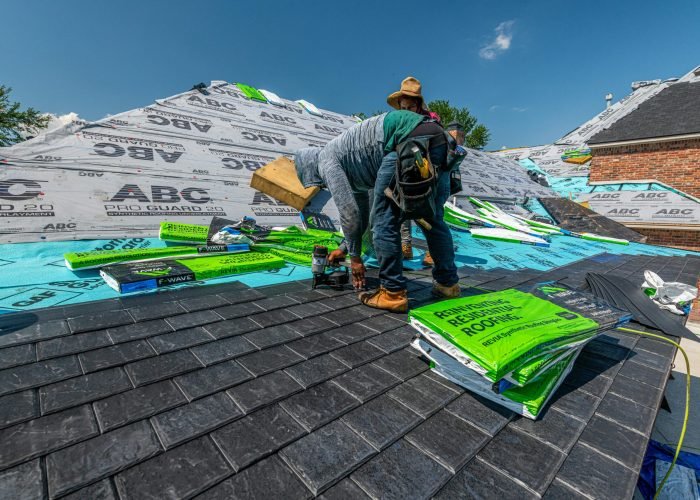 Workers installing a synthetic slate roof on a brick house in Fort Worth, Texas.
