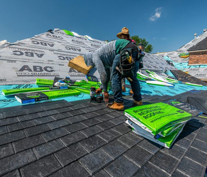 Workers installing a synthetic slate roof on a brick house in Fort Worth, Texas.