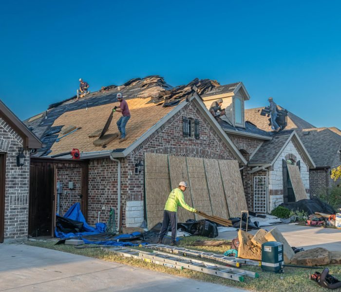 Workers engage in roof replacement on a brick house in Fort Worth, Texas.
