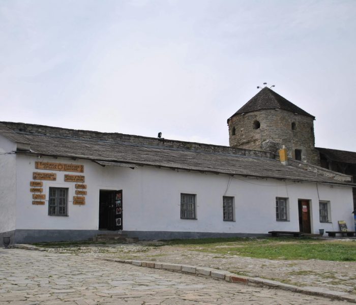 A historic stone tower with a white building exterior under a clear sky, showcasing classic architecture.