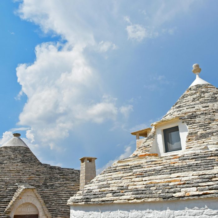 Traditional trulli houses in Puglia with unique conical roofs under a vibrant blue sky.