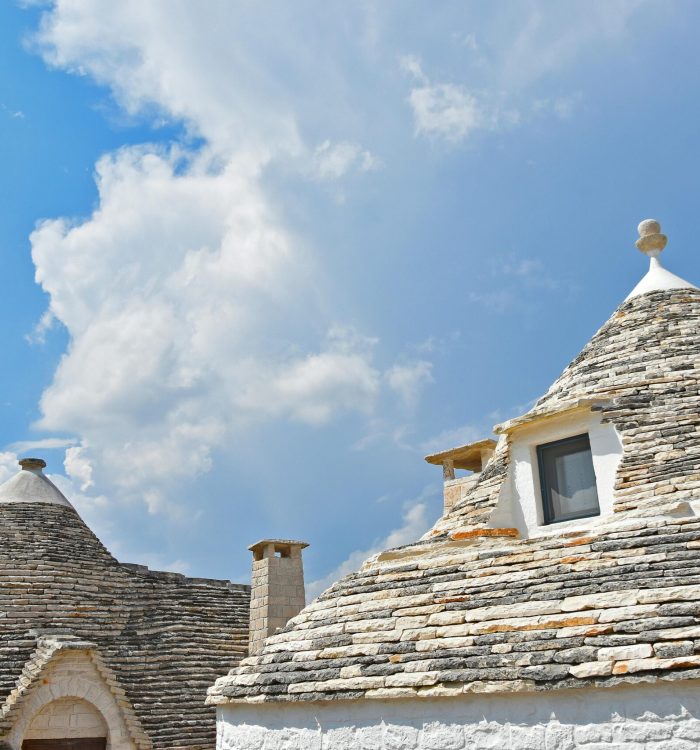 Traditional trulli houses in Puglia with unique conical roofs under a vibrant blue sky.