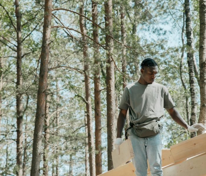 Man working on wooden construction in forest, showcasing carpentry skills.
